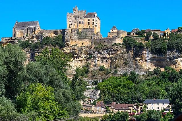 Château de Beynac perched on its limestone cliff above the Dordogne valley under a deep blue sky